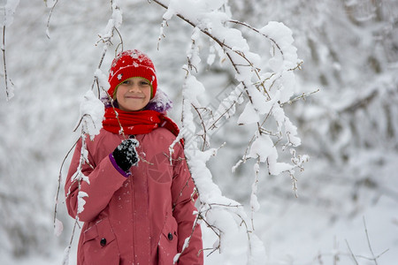 快乐的女孩站在雪树下枝的丛里图片