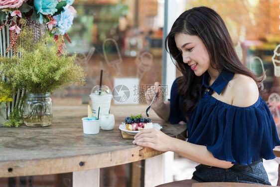 在咖啡馆吃蓝莓奶酪蛋糕的年轻女子图片