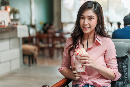 在咖啡馆里拿着草莓冰淇淋的年轻女子图片