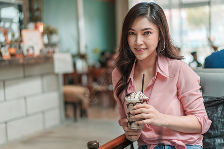 在咖啡馆里拿着草莓冰淇淋的年轻女子图片