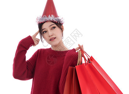 年轻思考和持有购物袋的年轻女在白色背景下被孤立圣诞节概念图片