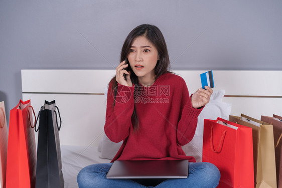 妇女用智能手机和信卡在线床上购物图片