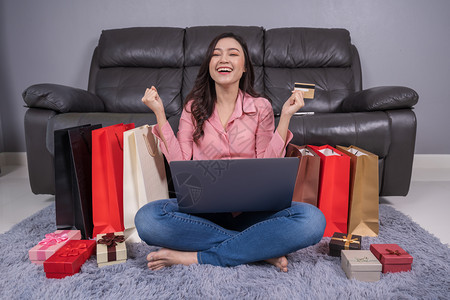 开心的女人用笔记本电脑在客厅用信卡成功在网上购物图片