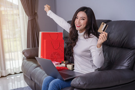 开心的女人用笔记本电脑在客厅用信卡成功在网上购物图片