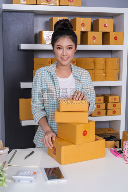 青年女创业者在她自己的工作岗位上拥有包裹箱的女青年创业者在家网上购物图片