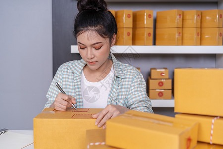 年轻女创业者在包裹箱线商业分娩前准备工作上写图片