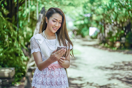 使用智能手机穿泰国传统服装的年轻美女图片