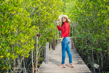 身着红色衣服的妇女在泰国Rayong省TungProngThong或金红田的木桥上穿着红衣图片