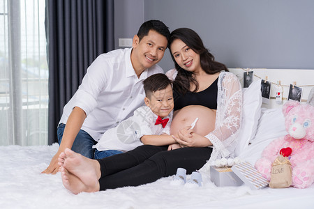 幸福家庭概念怀孕母亲父和儿子在床上进行怀孕测试图片