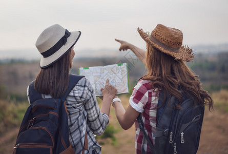 2名妇女旅行者在时地点图上搜索方向图片