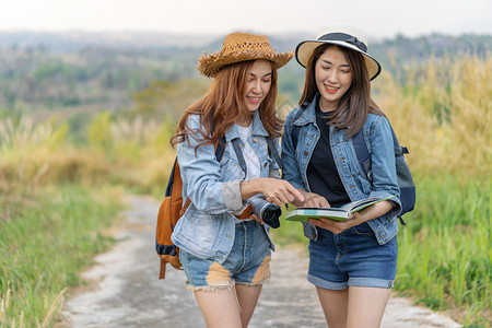 2名妇女旅行者在时地点图上搜索方向图片