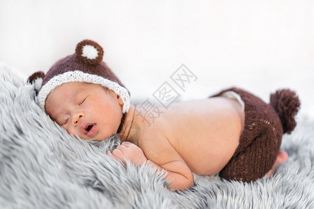 熊帽中新生婴儿睡在毛皮床上图片