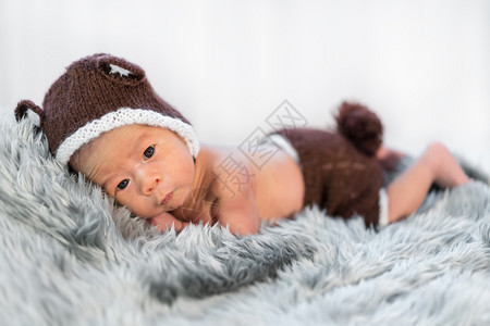 灰色泰迪在毛皮床上戴熊帽的新生婴儿背景