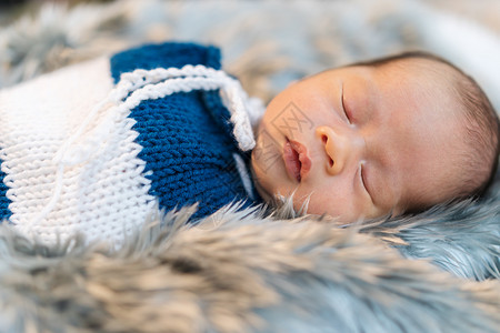 新生婴儿男孩睡觉和在床上的毛巾包装中摇晃地躺在床上图片