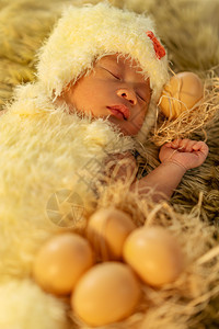 身着鸡装的新生婴儿睡在毛皮床上图片