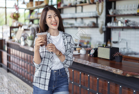年轻女子在咖啡馆里喝着冰巧克力奶茶图片素材