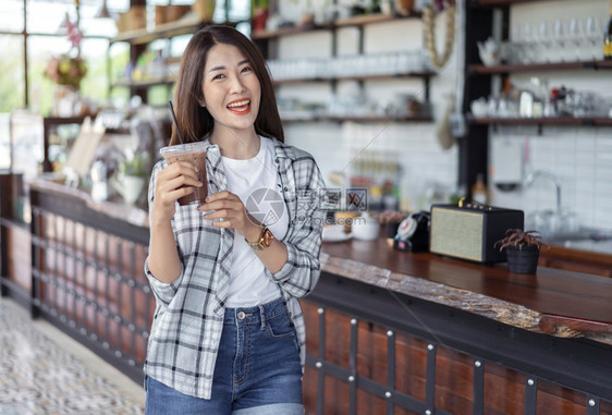 年轻女子在咖啡馆里喝着冰巧克力奶茶图片