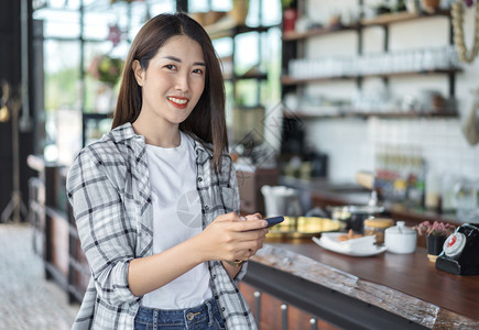 在咖啡馆里使用智能手机的快乐女人图片