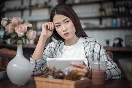 妇女使用数字平板电脑和在咖啡厅思考图片