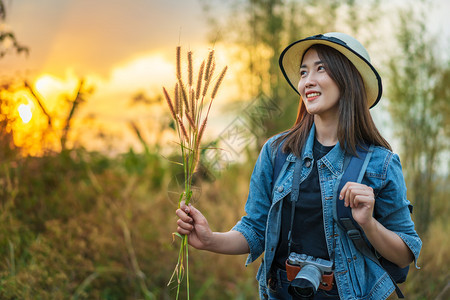 携带背包和照相机的女旅游客在农村日落图片