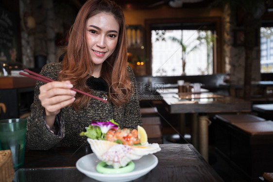 女人在餐厅里吃鲑鱼生辣色沙拉图片