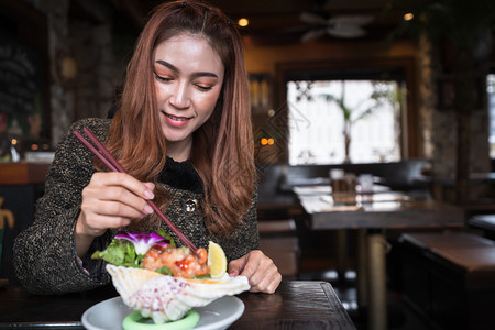 女人在餐厅里吃鲑鱼生辣色沙拉图片