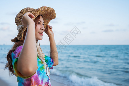 女人戴帽子站在海边的图片