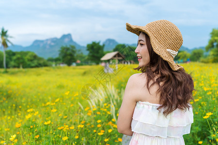 在黄色宇宙花朵田中快乐的女子图片