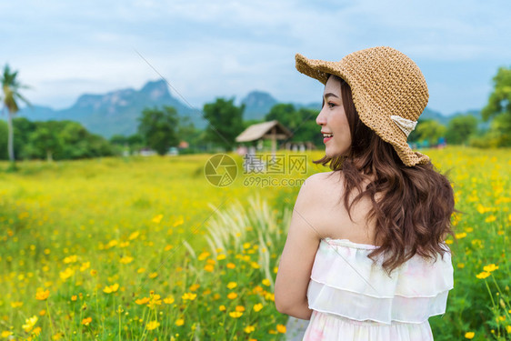 在黄色宇宙花朵田中快乐的女子图片