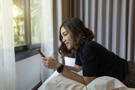 妇女在床上使用智能手机图片