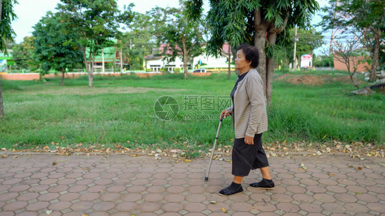 高级妇女在公园中带着拐杖走来去图片