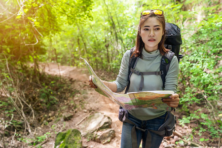 携带背包和在天然林中搜索方向的女旅行者图片