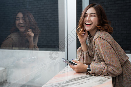 快乐的年轻女子手持智能机在窗口图片