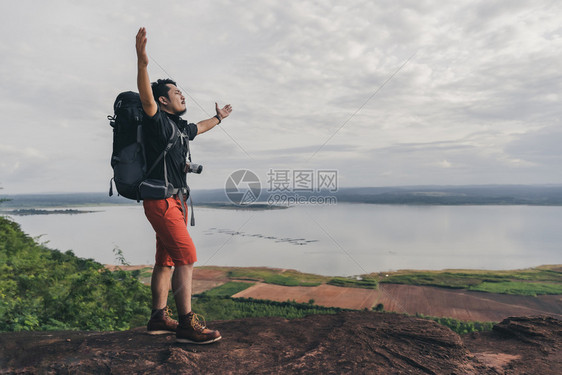 在悬崖边缘岩石山顶举起手臂图片