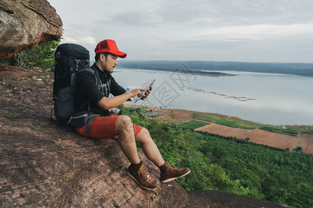 背着包的人旅行者看着悬崖边缘的岩石山顶的图片