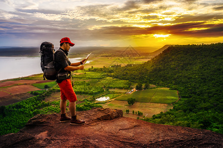 背着包的人旅行者看着悬崖边缘的日落时在岩石山顶图片