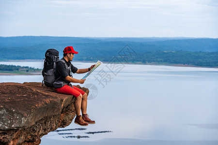 背着包的人旅行者看着悬崖边缘的岩石山顶的图片