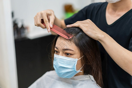 理发师给女客户人们必须用医疗面具来保护冠状新冠大流行病图片