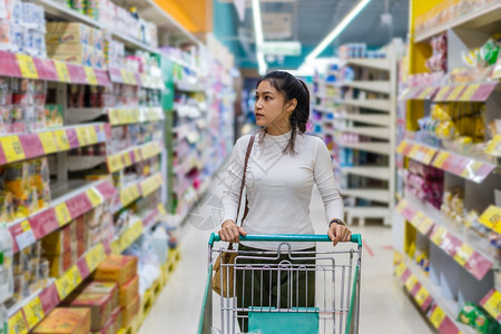 韩国超市在超市百货商店用购物车的年青少女背景