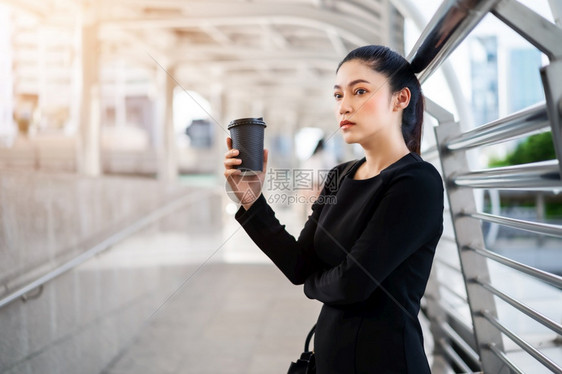 女人拿着一杯咖啡想她在城里的生意问题图片