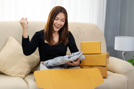开心的女人在家里客厅打开纸板包裹箱在网上商店购买图片