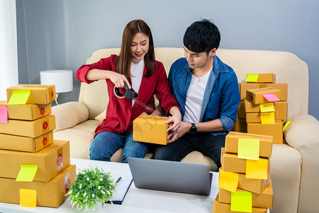 火柴包装夫妇在线创业者使用磁带在家庭办公室包装裹箱准备产品交付