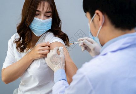 医生持有注射器并使用棉花然后医疗面具向病人注射图片