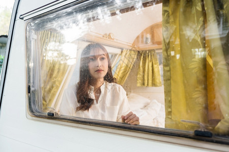年轻女在露营车RV面包马达之家的窗前看望着女青年图片
