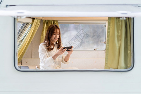 年轻女子在露营车RV面包汽旅馆的床上使用智能手机图片