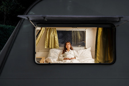 年轻妇女睡在一辆RV面包车摩托之家露营的床上图片