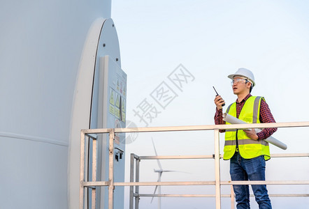年轻男工程师使用对讲机校验风力涡轮农场系统图片
