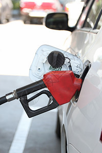 在加油站向汽车倾注的红色燃料喷嘴背景图片