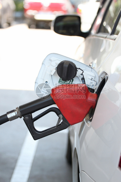 在加油站向汽车倾注的红色燃料喷嘴图片