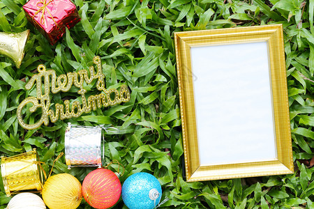 在绿草坪上的圣诞装饰品上面有圣诞快乐的金条地板上有色的空木框图片